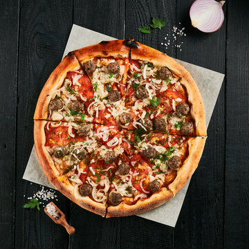 Homemade pizza with meatball on black wood background.  American pizza with meat and cheese. Italian pizza  in rustic style. Junk food on dark backgroundp87