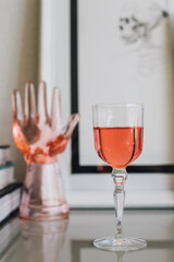 small glass of rose wine with pink glass hand, skeleton drawing in the background