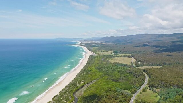 Stunning high angle aerial panoramic drone footage of Lagoons Beach Conservation Area and the A3 Tasman Highway near the village of Scamander on the east coast of Tasmania, Australia on a sunny day.