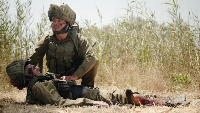 Soldier looking around lays down head colleague and drags seriously injured colleague on. Close up shot