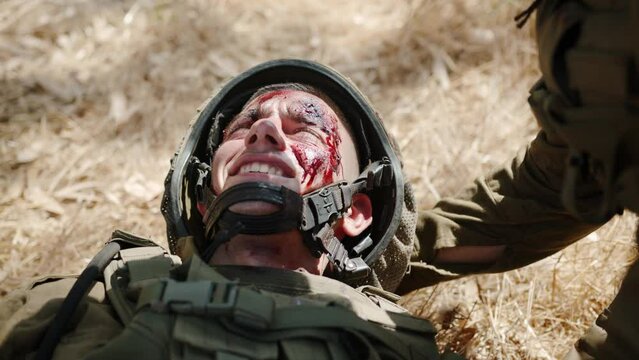 Severely wounded soldier breathing quickly tries to swallow the pain and hopelessly shakes his head. Close up shot
