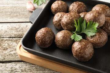 Tasty cooked meatballs with parsley on wooden table, closeup