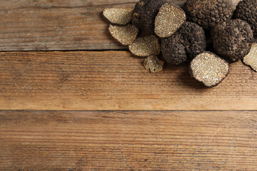 Naklejka premium Black truffles on wooden table, flat lay. Space for text