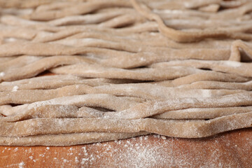 Uncooked homemade soba (buckwheat noodles) on wooden table, closeup