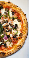 A vegetarian Neapolitan pizza topped with mushroom, black olives, green bell peppers, onions, mozzarella cheese in a white pizza box background.