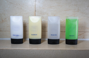 A toiletry set of Body Lotion,  Conditioner, Shower Gel and Shampoo on a shower shelf.
