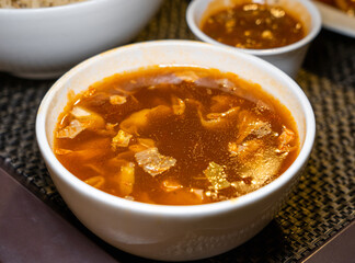 Close up of Hot and Sour vegetarian soup in a white ceramic bowl.