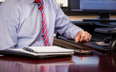 Man in shirt and tie in office settinf with computer in background