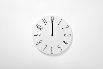 Stylish analog clock hanging on white wall