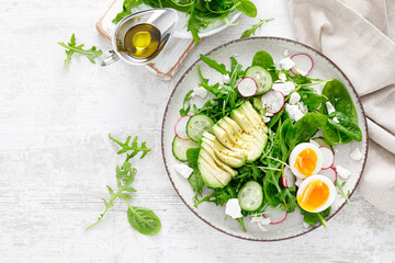 Avocado and boiled egg fresh vegetable salad with radish, cucumber, spinach, arugula and cottage cheese. Top view