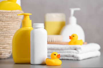 Obraz na płótnie Canvas Baby cosmetic products, towel and rubber ducks on grey table, space for text