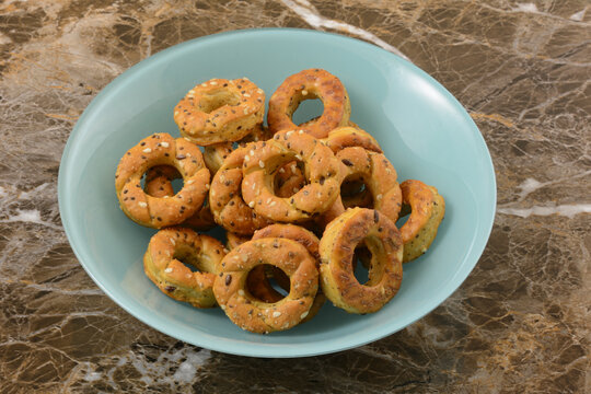 Pretzel Cracker Rings With Topping Of Sesame Seeds, Chia, And Flax Seeds In Blue Snack Bowl