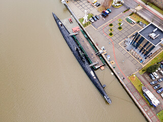 black submarine surfaced on the water in the city harbor.