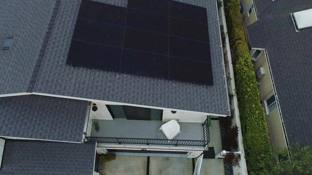 Drone over and tilt up on rooftop solar panels with worker in background in Los Angeles, California