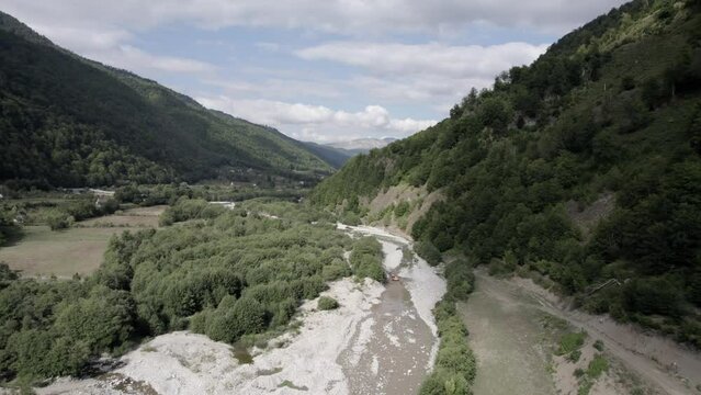 Drone video of a shot over an excavator machine working on the Vermoshi River in the Vermosh valley, the sh20 at the height of Bashkimi, Albania. you can see small houses of the town