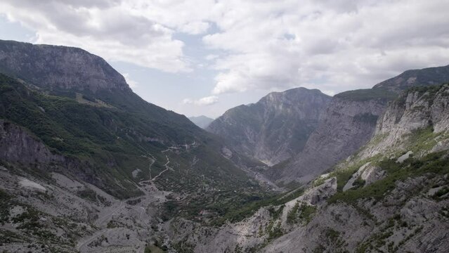 Drone video of frontal plane advancing on the Sh20 highway in Albania, at the height of Javor and Mreg with both towns in the scene, small houses of the town can be seen, cloudy sky.