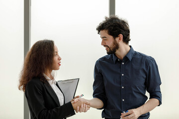 Caucasian bearded male businessman employee and African American female businesswoman colleague coworker in formal black suit working discussing together at workplace office.