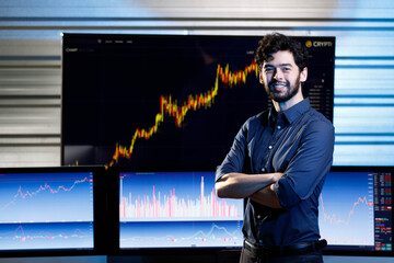 Portrait shot of Caucasian professional successful bearded male businessman broker in casual outfit standing crossed arms smiling look at camera in stock trading room with computer screen monitor