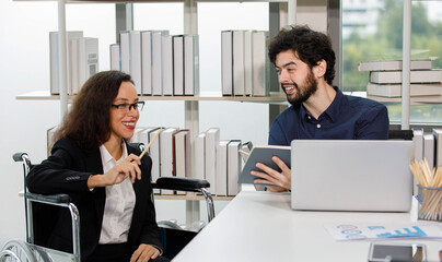 Caucasian bearded male businessman employee and African American female businesswoman colleague coworker in formal black suit sitting working discussing together at workplace office.