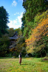 新潟県の佐渡島にある清水寺で神社仏閣めぐりをするひとり旅の女性（秋）
