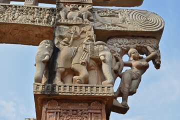 Stupa No 1, East Gateway. Pillar capitals are supported by four elephants. Carved damsels or Shalabhanjikas are seen clinging to tree - obrazy, fototapety, plakaty