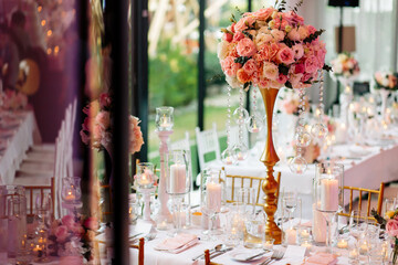 View Of A Beautiful Table Arrangement Of Pink Roses, White Candles And Table Cloth During A Wedding