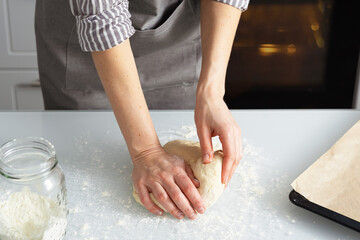 A woman is in the kitchen baking bagels with jam. Sweet pastry with your own hands. Woman kneading dough for baking.