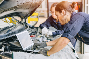 Meachnic staff worker using laptop computer check ane tuning car engine in garage