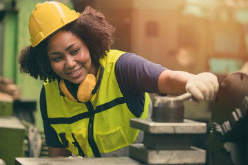 African American woman worker happy smiling working with metal machine in heavy industry factory - obrazy, fototapety, plakaty