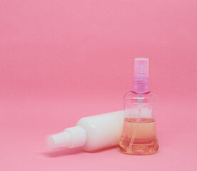 Two spray bottles on a pink background