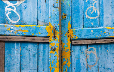 Close up on old blue and yellow wooden doors in outdoor.