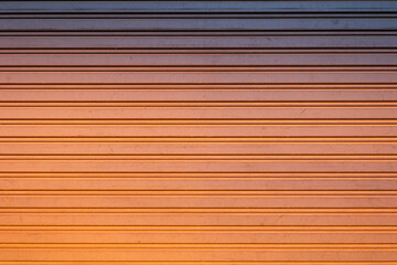 Backdrop of metal wall touching orange sunlight.