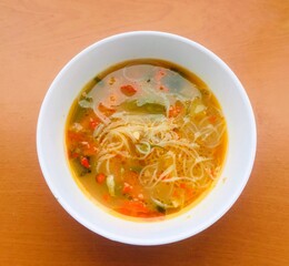 A bowl of vegetable soup and vermicelli or rice noodles.
