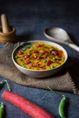 Indian food dal tadka or lentil soup served in a bowl along with condiments.