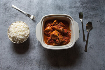 Popular meal chicken masala curry in a bowl served along with steamed rice. Top view.