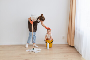 Full length portrait of woman housekeeper wearing orange rubber gloves, brown apron and jeans...
