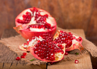 Juicy pomegranate and its half Beautiful composition with juicy pomegranates, on old wooden table