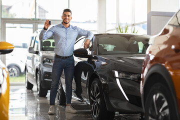 Successful middle-eastern businessman buying new sports car, full size shot