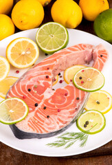 Steak of red fish and sliced lemons on wooden table