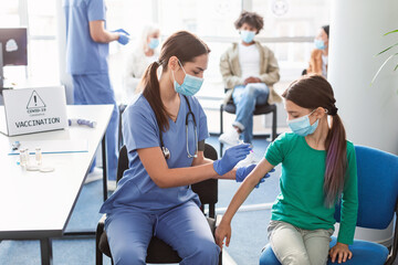 Obraz premium Teen Girl Receiving Vaccine Injection In Arm In Health Center