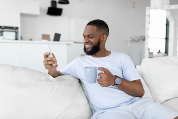Black guy texting on his smartphone drinking coffee