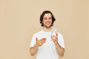 Attractive man in a white T-shirt with a mug in hand beige background