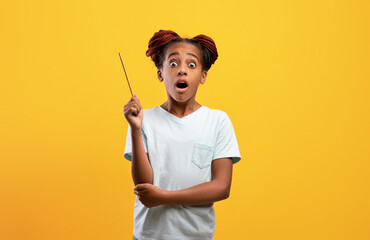 Amazed black girl teenager raising pencil up