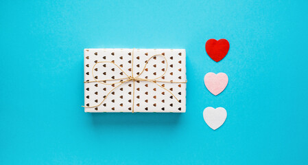 Valentine's day composition with gift box and hearts on blue background. Wedding, birthday, woman's and mother day concept. Flat lay, top view, copy space, place for text, empty, mock up, banner