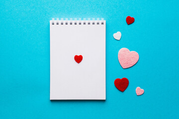 Valentine's day composition with notebook list and hearts on blue background. Wedding, birthday, woman's and mother day concept. Flat lay, top view, copy space, place for text, empty, mock up, banner