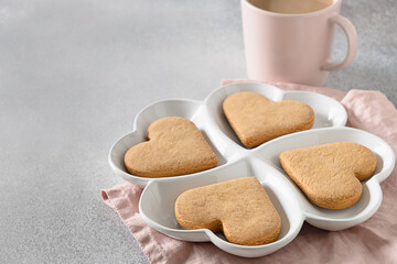 Heart shaped cookies on white combination plate for Valentine's Day on gray background. View from above. Space for your greetings.