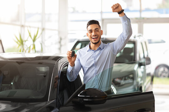 Emotional middle-eastern guy raising hand up, showing car key