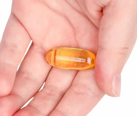Foto op Plexiglas Lieve mosters Close up van visolie capsule op een hand geïsoleerd op een witte achtergrond
