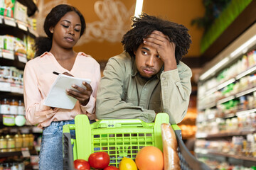 African Couple Struggling During Financial Crisis Calculating Supermarket Prices Indoor