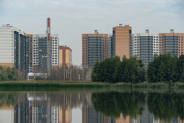 Fototapeta na wymiar New modern residential apartment buildings by the lake surrounded by green trees and grass.reflection of buildings on smooth water